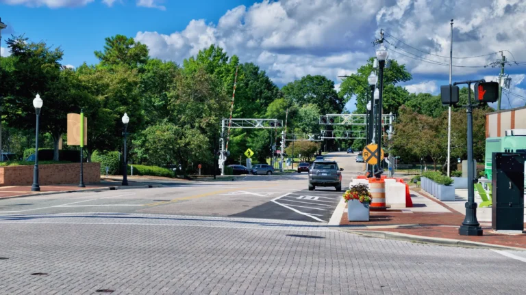 Brick-paved intersection with crosswalks, traffic signals and railroad crossing gates ahead