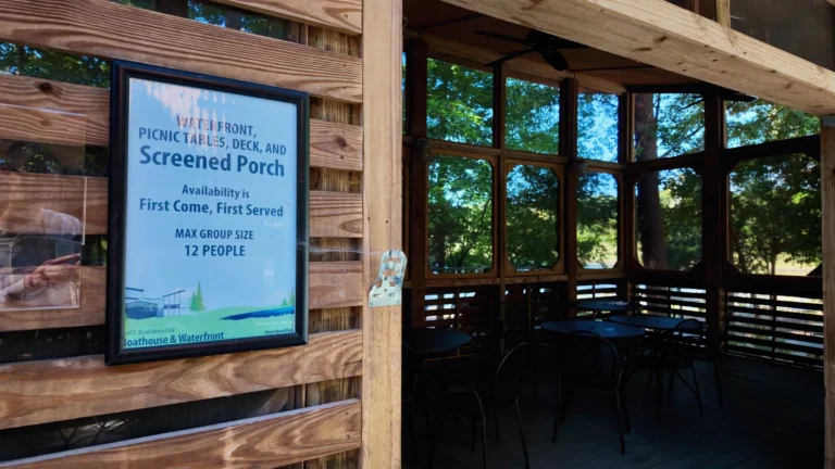 Sign reading Waterfront, Picnic Tables, Deck, and Screened Porch, First Come First Served, beside an empty screened porch