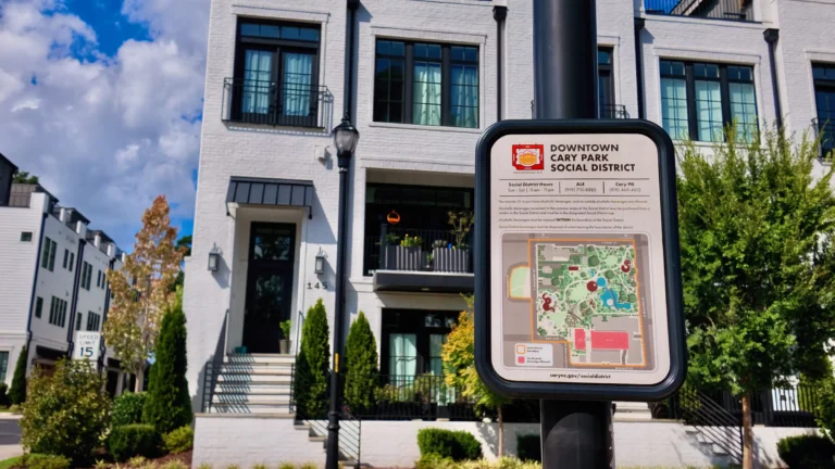 Downtown Cary Park Social District sign with a map, mounted on a lamppost in front of white townhomes