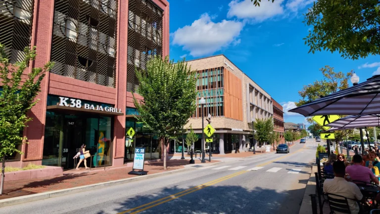 View down East Chatham Street with a K38 Baja Grill storefront and patio diners under umbrellas