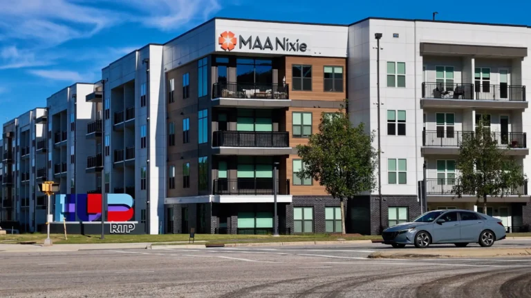 Five-story apartment building with wood-tone panels and balconies beside the colorful Hub RTP sign