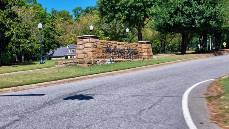 Stacked-stone entrance wall with dark script lettering for MacGregor Downs, lampposts on top
