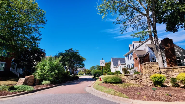 Brick-paved side street entrance with a stacked-stone wall, shrubs and two-story homes